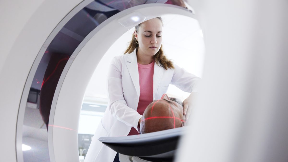 Female radiologist helping patient in medical x-ray scanner - stock photo