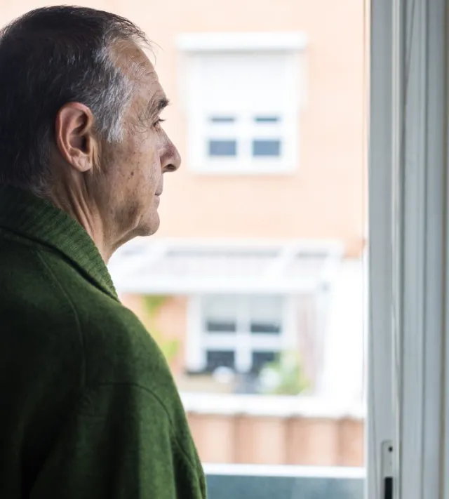 Senior man with Alzheimer's and depression, sideways, looking out the window. Concept of old age, disease, loneliness, forgetfulness and memory. - stock photo