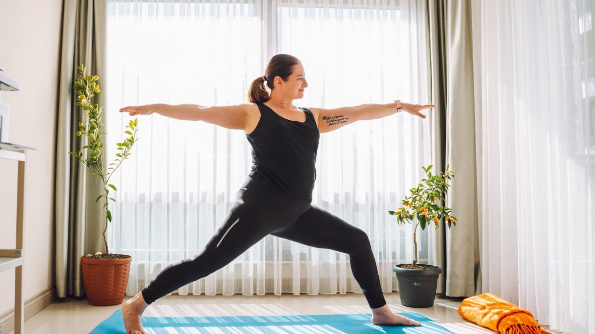 Woman plus size practicing yoga at home in living room - stock photo