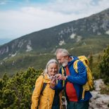 Elderly couple taking selfie while hiking together in autumn mountains. - stock photo
