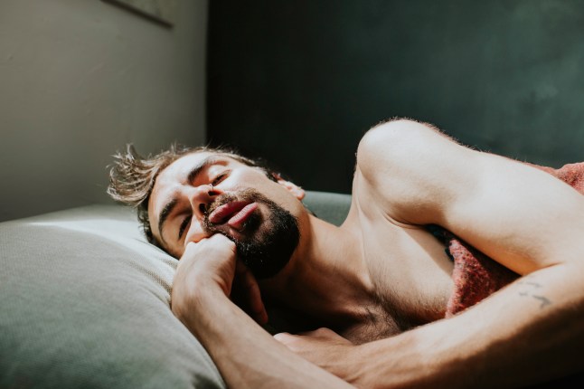A man in a deep, restful, sleep as bright sunlight shines down on him through a window