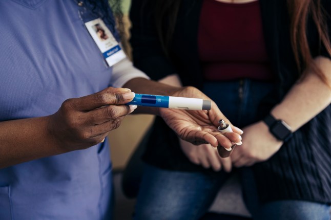 Hand of female nurse holding weight loss injection pen in exam room at doctor's office