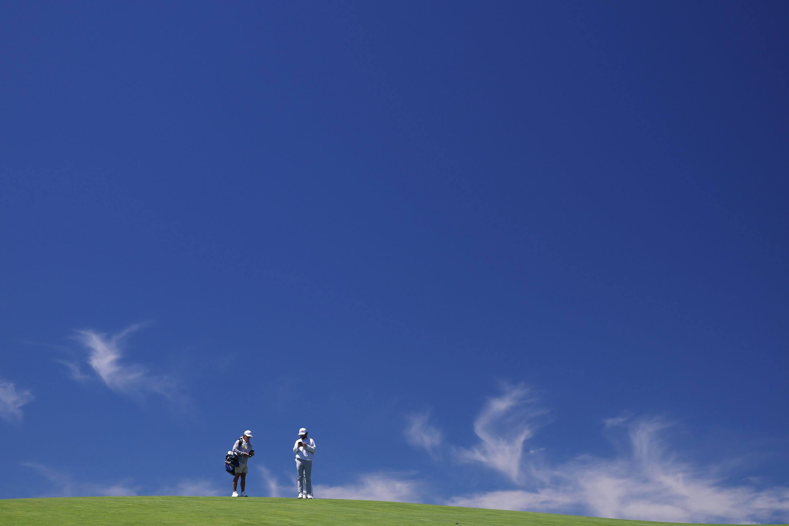 Cameron Young and his caddie look at their yardage books during Monday's practice round at Shinnecock Hills.