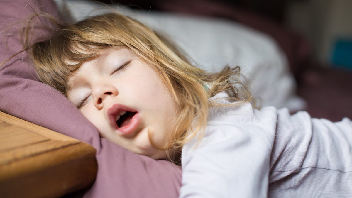 Funny face of child sleeping on king bed - stock photo