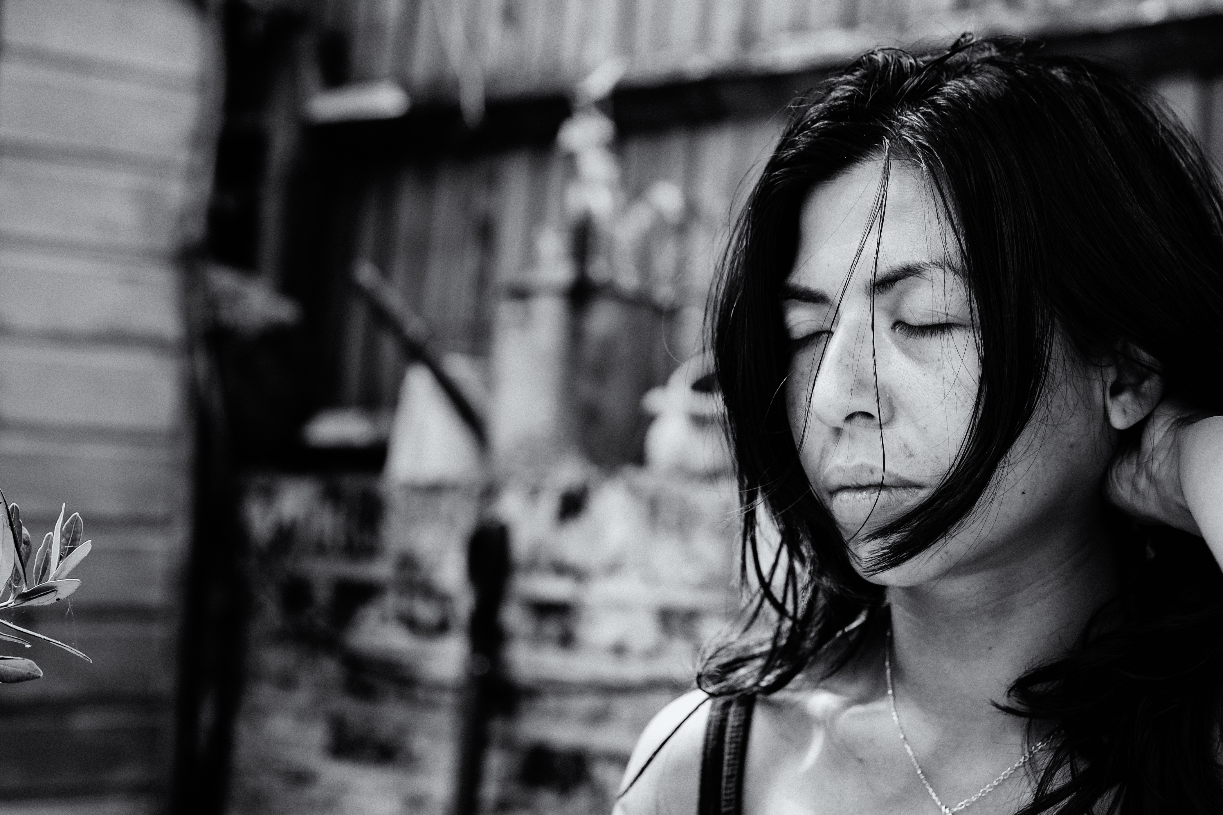 Annalisa stands in her garden with eyes closed and hair blown across her face, her expression still and inward at the end of a demanding day.