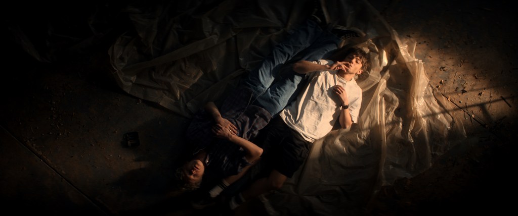 Leviticus still: two boys lying down on the floor, one smoking