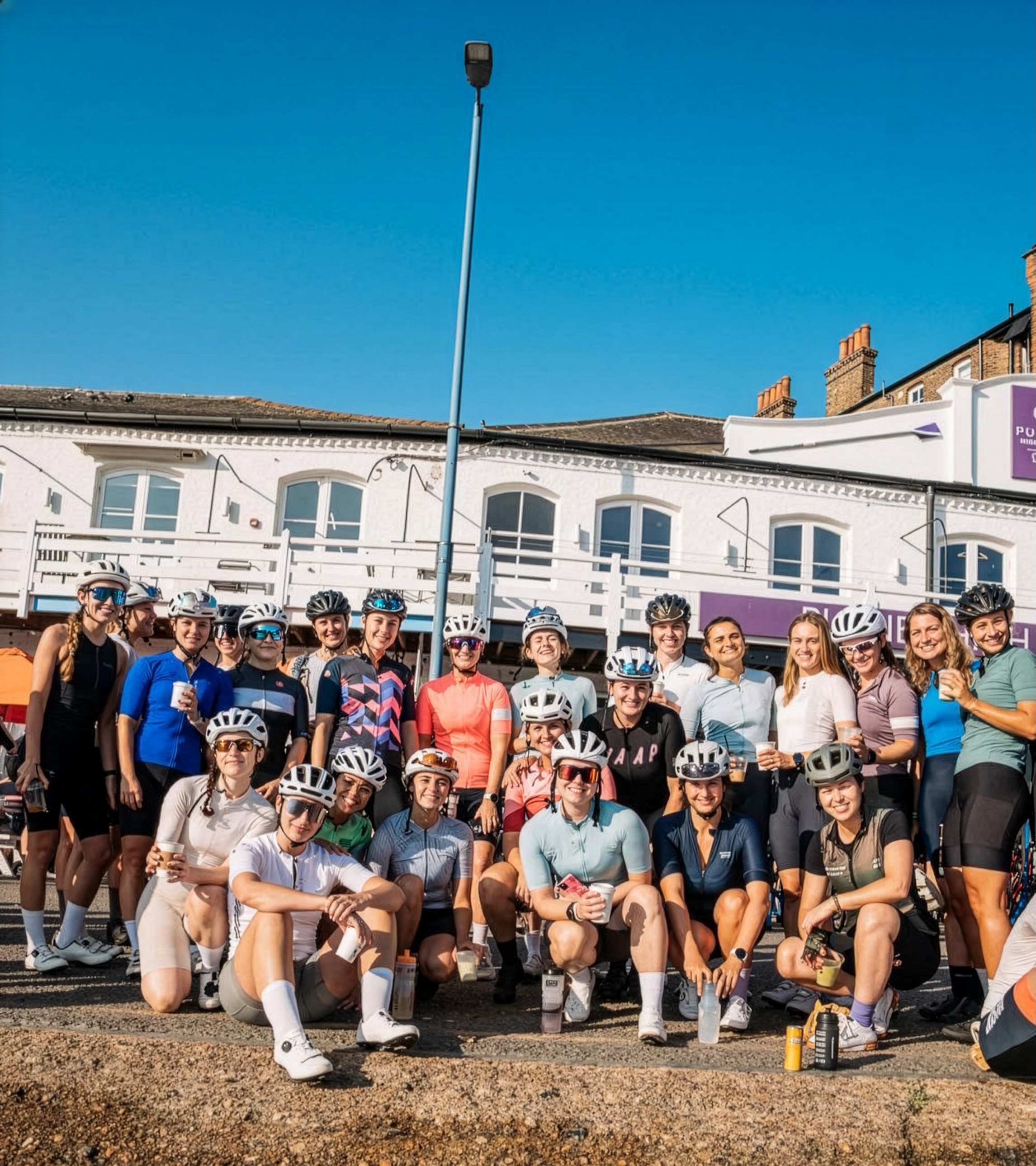 A group of cyclists posed outside some white buildings in the UK