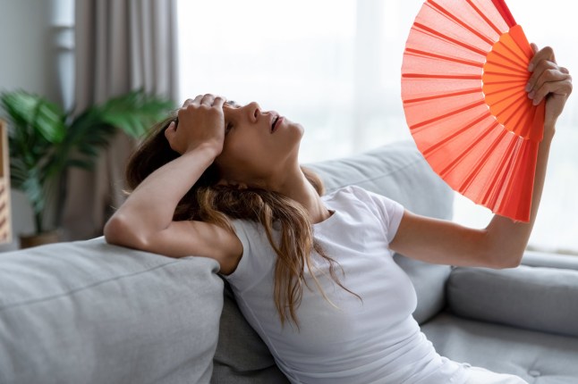Side view exhausted young biracial girl using paper waver, suffering from hot summer weather or high temperature at home. Unhappy overheated millennial mixed race woman feeling uncomfortable indoors.; Shutterstock ID 1536165167; Purchase Order: -