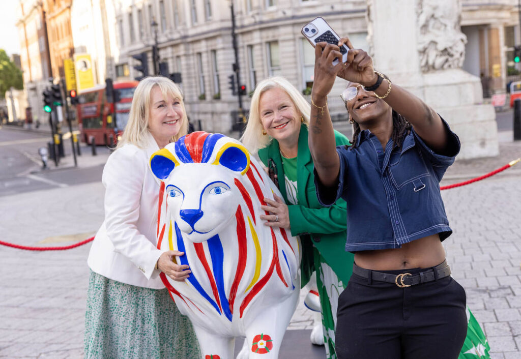 three people taking a selfie with a sculpture of a lion with a unique design