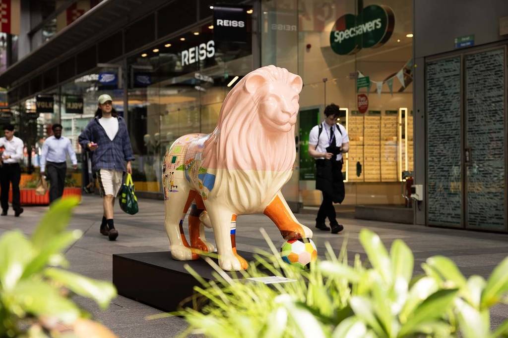 a sculpture of a lion with a unique design, with one foot atop a football