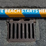 WEYMOUTH, ENGLAND - OCTOBER 19: Street art drawing attention to pollution caused by rainwater drains which take untreated surface water, or storm water, directly to rivers and beaches with the words, 'The Beach Starts Here' is seen at a road drain on October 19, 2021 in Weymouth, United Kingdom. (Photo by Finnbarr Webster/Getty Images)