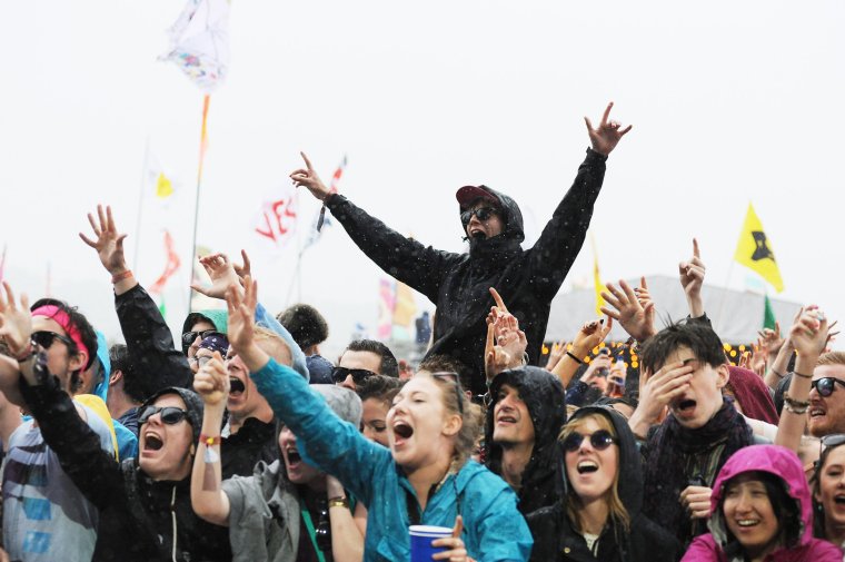 GLASTONBURY, ENGLAND - JUNE 26: A festival goer enjoys the music, regardless of the rain, sat on the shoulders of another in the crowd at the Glastonbury Festival at Worthy Farm, Pilton on June 26, 2015 in Glastonbury, England. (Photo by Tabatha Fireman/Redferns via Getty Images)