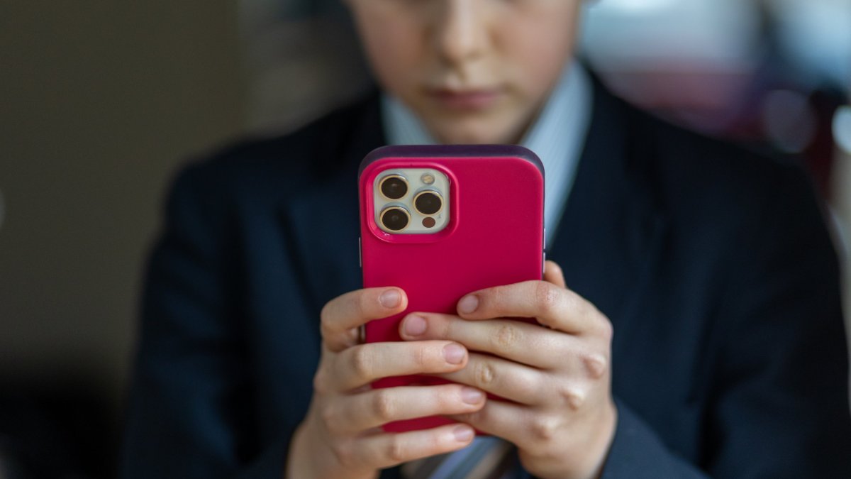 BATH, UNITED KINGDOM - FEBRUARY 25: In this photo illustration a a 12-year-old school boy looks at a iPhone screen on February 25, 2024 in Bath, England. This week the UK government issued new guidance backing headteachers in prohibiting the use of mobile phones throughout the school day, including at break times. Many schools around the country are already prohibiting mobile phone use over concerns. The amount of time children spend on screens each day rocketed during the Covid pandemic by more than 50 per cent, the equivalent of an extra hour and twenty minutes. Researchers say that unmoderated screen time can have long-lasting effects on a child's mental and physical health. Recently TikTok announced that every account belonging to a user below age 18 have a 60-minute daily screen time limit automatically set. (Photo by Matt Cardy/Getty Images)
