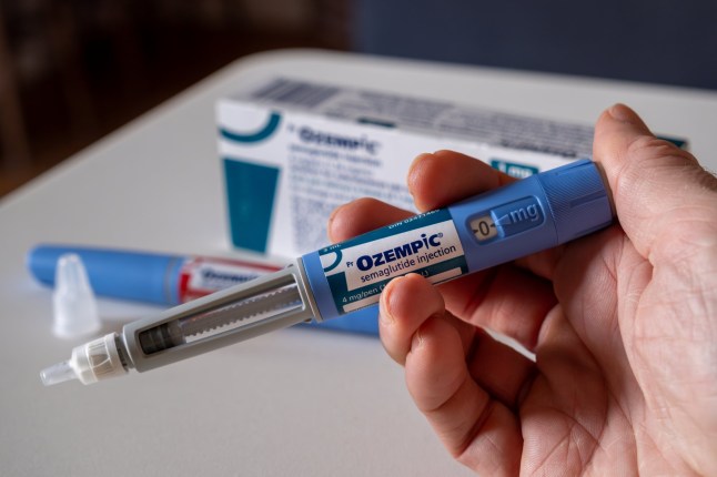 Hand holding Ozempic semaglutide injection pen.