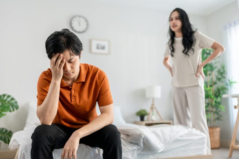Asian stressed woman and aggressive man screaming at each other in house. New marriage couple arguing and fighting, feel heartbroken for quarrel conflict in bedroom. Family problem-separation concept.