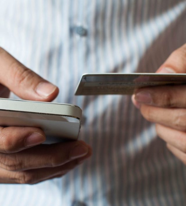 A businessman is buying online using his mobile phone and credit card
