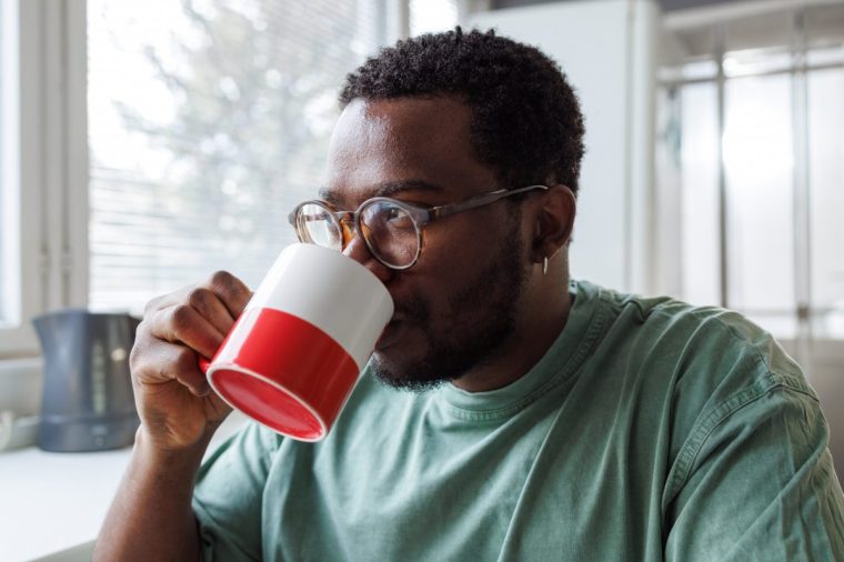 Young African American man drinking coffee during breakfast at home