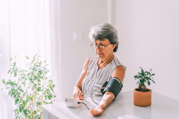 A woman takes her blood pressure at home.