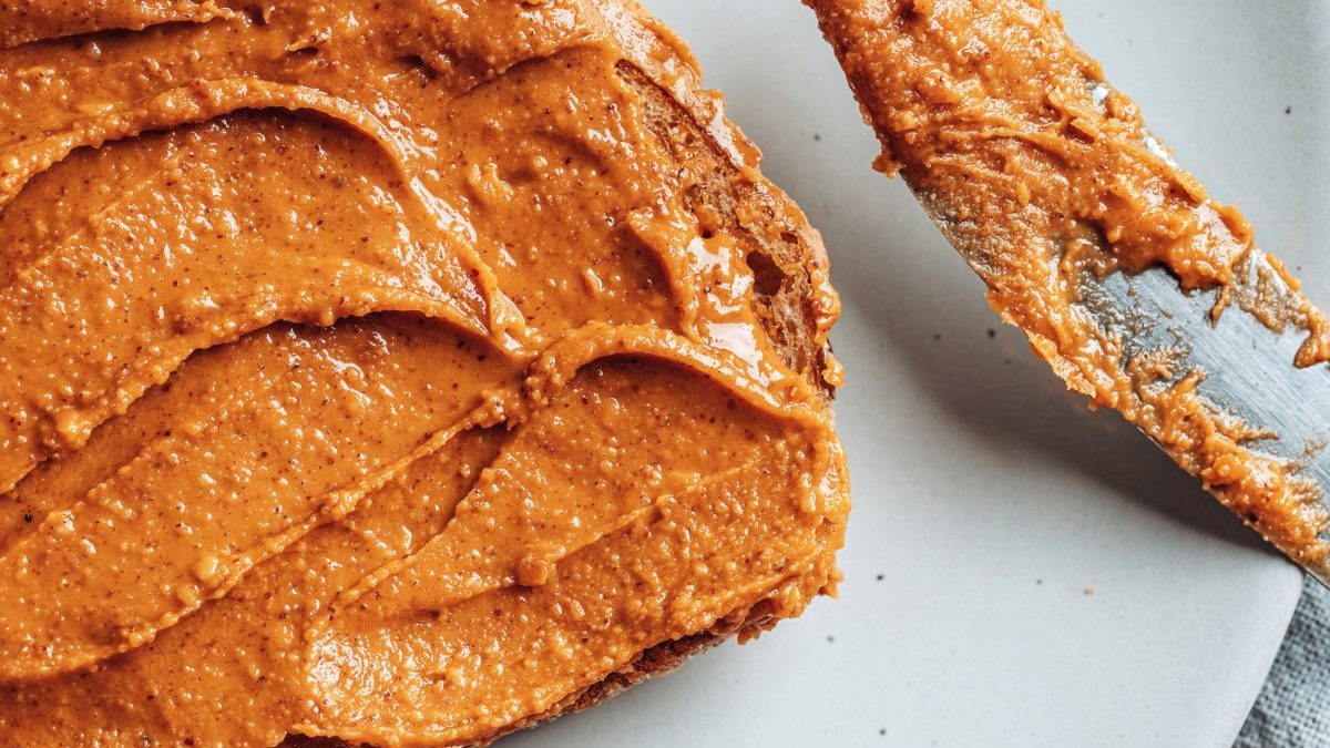 Close-up of peanut butter on toasted bread on light gray plate. Food background.