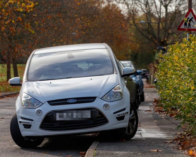 Milton Keynes,Bucks,UK -Nov. 8th 2025: Line of cars parked on the pavement next to a road sign warning of frail and elderly pedestrians.