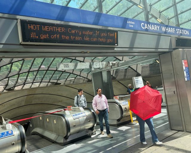 Tube passengers pass underneath hot weather health advice messages on LED screens outside the Canary Wharf Underground Station in London, Britain, May 26, 2026. REUTERS/Suzanne Plunkett