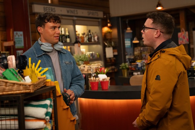 Lewis speaks to Vinny in the shop in Emmerdale