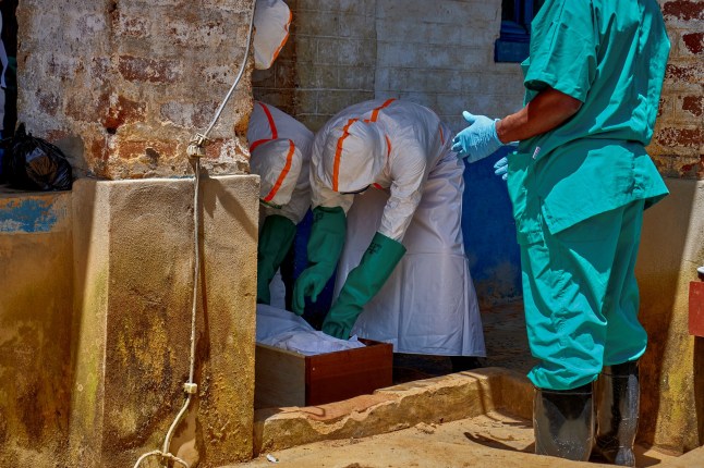 Red Cross workers wearing personal protective equipment (PPE) load the body of a child who died of Ebola into a wooden coffin while his parents remain at the isolation centre at the Mongbwalu General Referral Hospital, as aid agencies intensify efforts to contain a new Ebola outbreak involving the Bundibugyo strain, in Mongbwalu, Djugu Territory of Ituri province, Democratic Republic of the Congo, May 24, 2026. REUTERS/Gradel Muyisa Mumbere