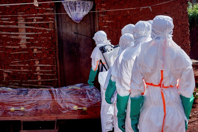 Red Cross workers wearing personal protective equipment (PPE) walk in a formation as they disinfect the house of an unidentified man who died of Ebola, before retrieving his body. (Picture: Reuters)