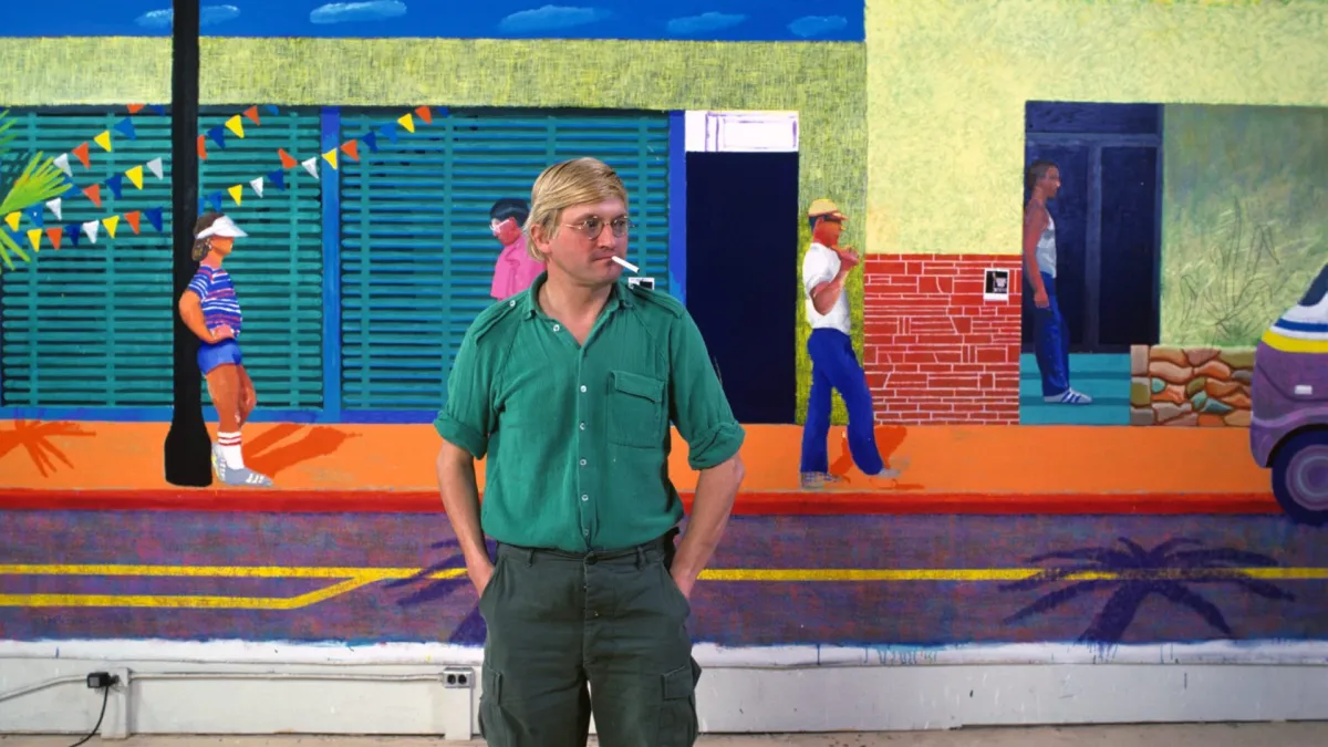 FILE PHOTO: Artist David Hockney dies aged 88 English artist David Hockney poses in front of a large painting of a street scene in his studio, 1980. (Photo by Susan Wood/Getty Images)
