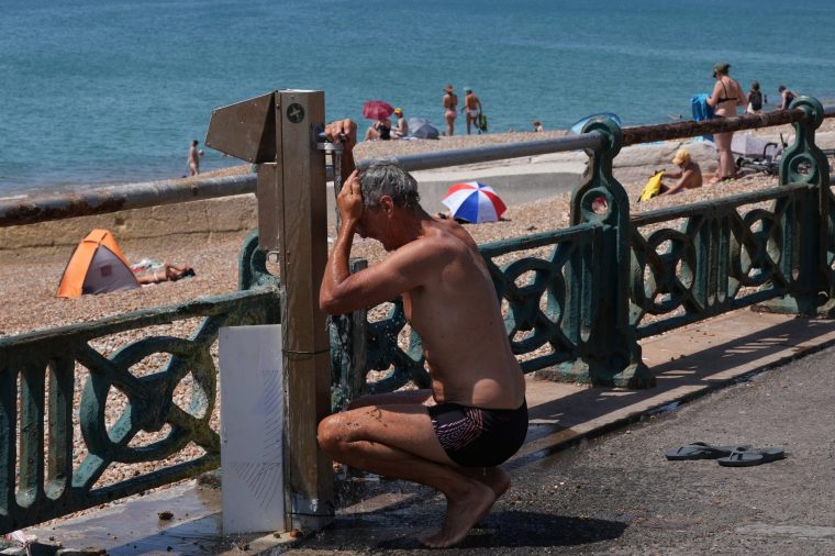 A person cools off with fresh water from a water fountain, by the beach in Hove, on the south coast of England on June 25, 2026, during a heatwave. The UK recorded its hottest ever June temperature on June 24 with the mercury rising to 36.1C in southern England, breaking the previous record of 35.6C set in 1976. (Photo by CARLOS JASSO / AFP via Getty Images)