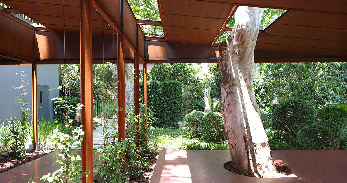 trees grow through this rust-colored coffee shed in a shanghai park