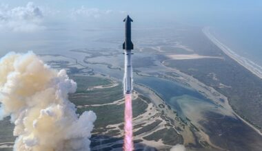 A rocket launches into the sky above a coastal landscape, leaving a trail of smoke and flames behind as it ascends over water and marshland.