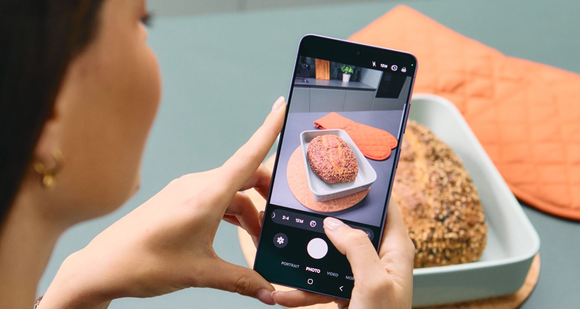 A woman takes a photo of a loaf of bread using a Samsung Galaxy S26 Ultra