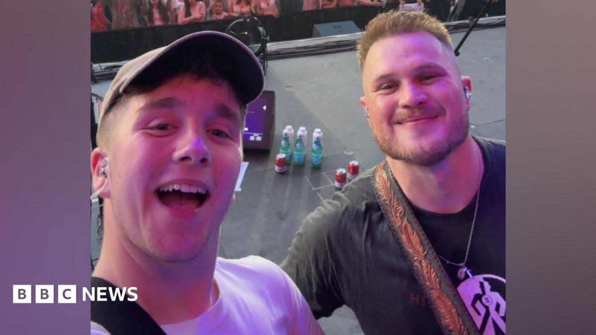 The image is a selfie of Paul with Zach Bryan. They are standing on a stage.