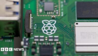 A close up of a Raspberry Pi computer with the white logo of a raspberry