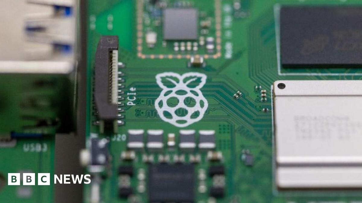 A close up of a Raspberry Pi computer with the white logo of a raspberry