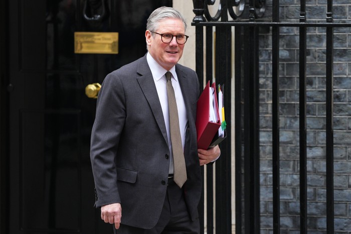 Sir Keir Starmer walking out of 10 Downing Street holding some folders.