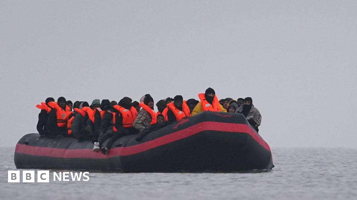 A small inflatable boat is on the water with a number of people wearing inflatable life jackets