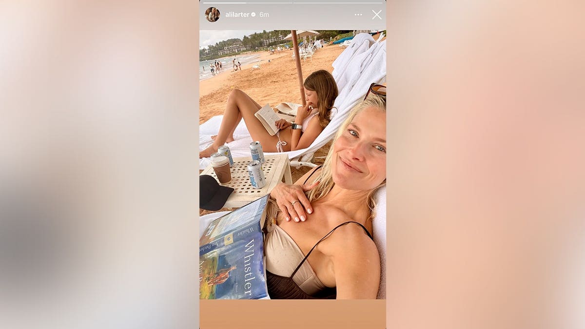 Ali Larter in a black bikini next to her daughter while at the beach.