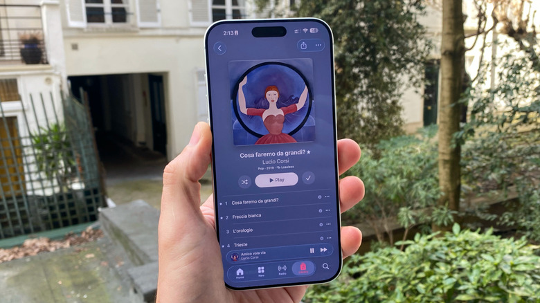A hand holding an iPhone with Apple Music opened up