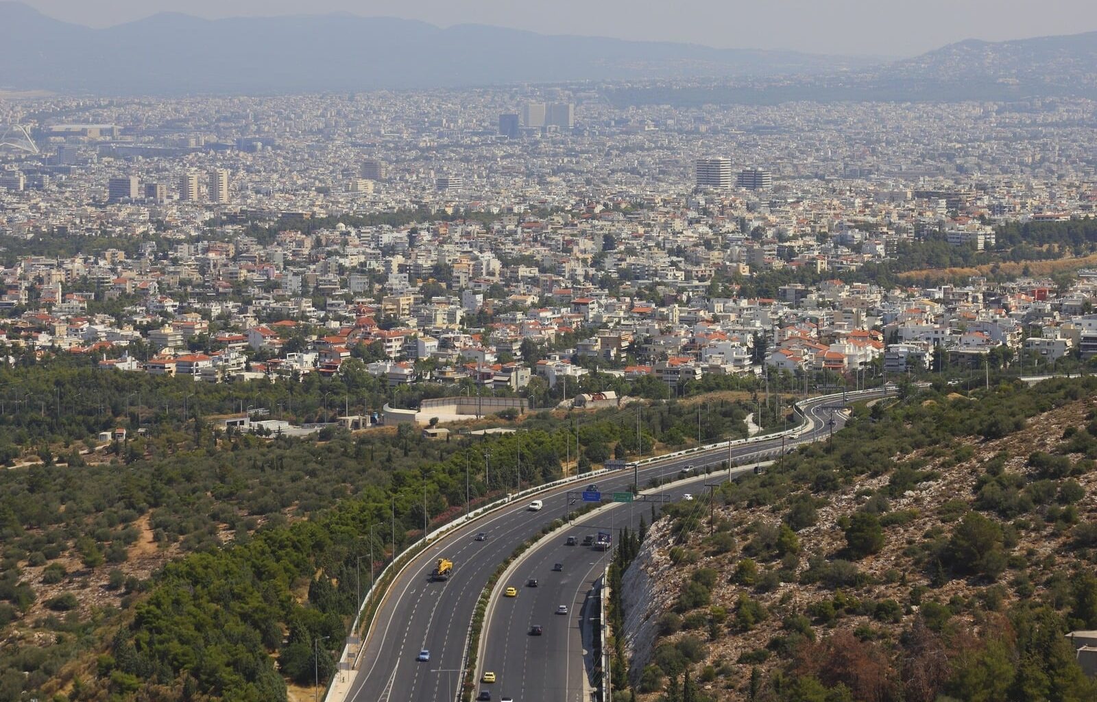 Aerial view of Athens and the Attica basin, showing dense residential areas and roads.