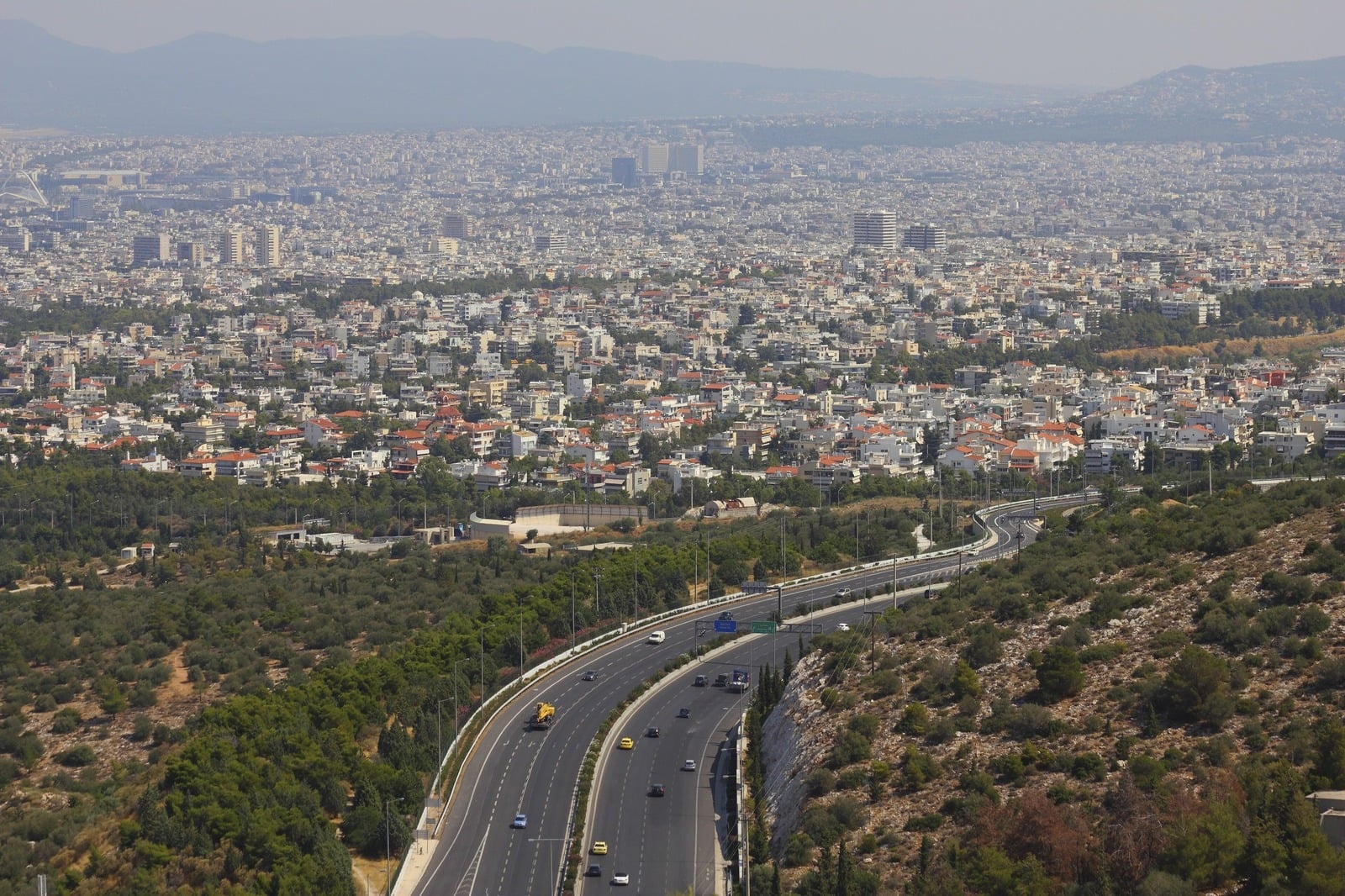Aerial view of Athens and the Attica basin, showing dense residential areas and roads.