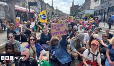 Leith demo - hundreds of protesters are sitting in a road with anti-racism banners