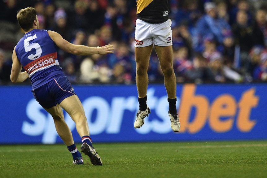 Football players play in front of a sportsbet banner.