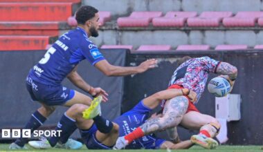 Josh Charnley (CHARNLEY 5) about to score a try on the right with two Toulouse players, one on the floor and one bending down, not being able to stop him