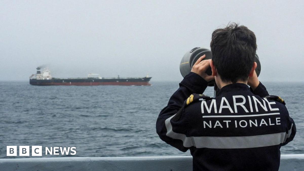A French Navy officer wearing a black uniform labelled Marine Nationale observes an alleged Russian oil tanker sailing in the Atlantic ocean.