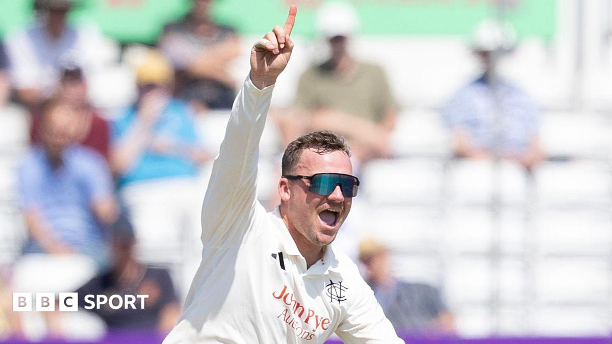 Liam Patterson-White celebrates taking a wicket by raising his right hand with his index finger pointing towards the sky.