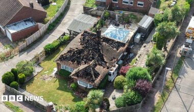 An aerial shot of a house with a heavily damaged roof.