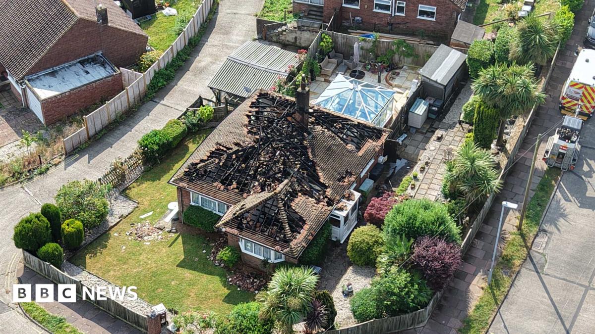 An aerial shot of a house with a heavily damaged roof.