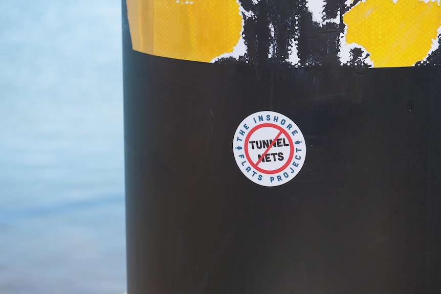 A sticker that reads "No tunnel nets" stuck to a pier pylon.